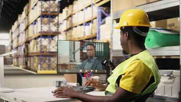 Warehouse clerk meeting on web call with manager on computer, transmitting order shipment details for parcels before distribution. Black man and CEO on remote videoconference. Camera A. video