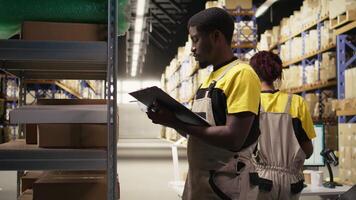 personal medlem applicering lim frakt etiketter på lådor i industriell depå, märkning paket med awb spårning tal till säkerställa sömlös uttrycka leverans och beställa bearbetning. kamera a. video