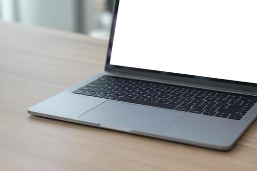 Sleek silver laptop computer with blank screen sits on a light wooden desk, representing modern workspace productivity and digital technology photo