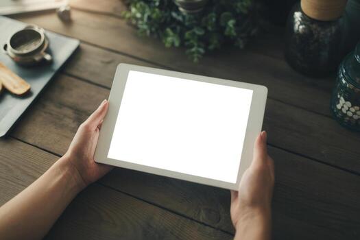 Woman using tablet computer with blank screen at rustic wooden table in cozy home office setting, showcasing technology and remote work concept photo