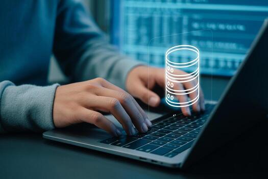 Person working diligently on laptop computer, managing a database at night in a modern office, symbolizing data management and cybersecurity photo