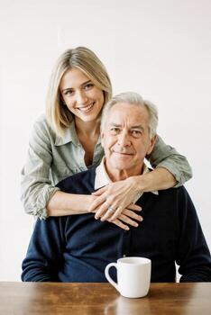 A woman is hugging an older man while sitting at a table photo