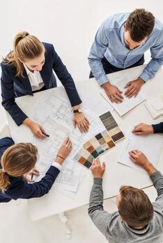 Four people sitting around a table with blueprints photo