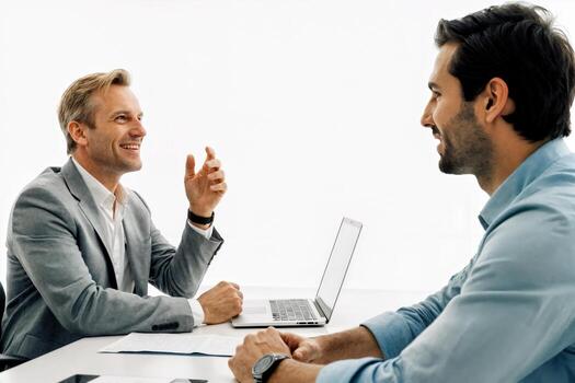 Two men talking at a table with a laptop photo