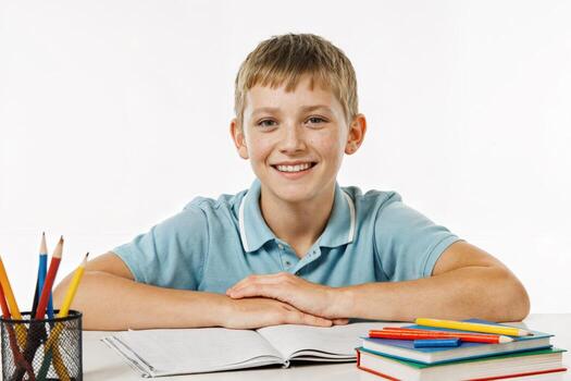 Young boy smiling at a desk with books and stationery during an educational activity at home photo