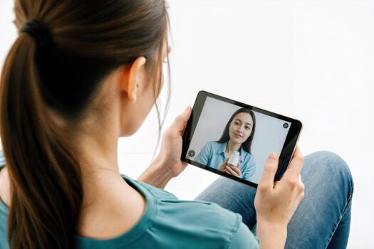 A woman is sitting on the floor holding a tablet computer and looking at a on the screen photo