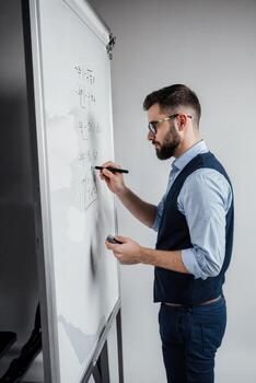 Business professional engages in presentation at a workshop while writing on a whiteboard in a modern office setting photo