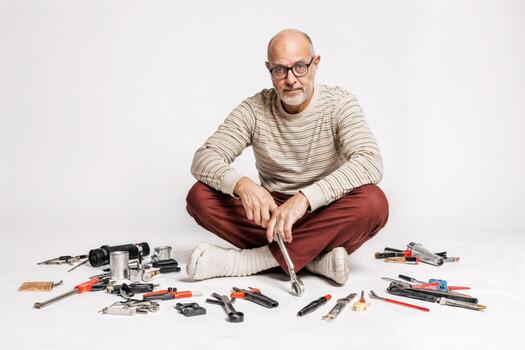 A man sitting on the floor surrounded by tools photo