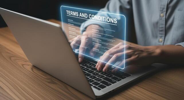 Person using a laptop reading terms and conditions agreement, digital contract compliance and policy review photo
