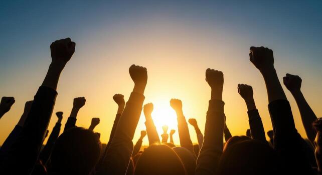 Group of people with raised fists silhouetted against the sky, symbolizing protest, unity and determination photo