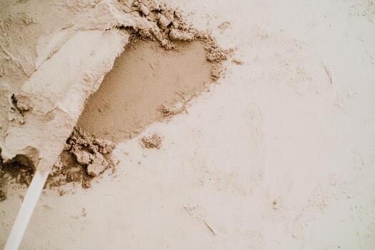 Construction worker applying cement mixture on smooth surface at job site photo