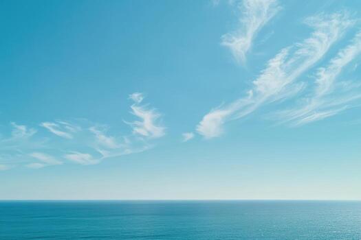 Vast ocean view beneath a clear blue sky with wispy clouds on a sunny day photo