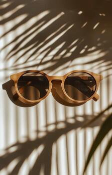 Stylish Wooden Sunglasses Placed on a Textured Surface With Shadow Patterns Created by Nearby Leaves. photo