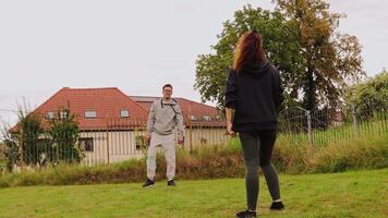 een paar is gezien hebben pret net zo ze leren naar Speel badminton in hun achtertuin. ze zijn ondersteunend van elk andere terwijl beoefenen hun vaardigheden in een ontspannen atmosfeer omringd door groen video
