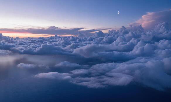 Aerial view of fluffy cumulus clouds stretching to horizon under dramatic twilight sky with moon photo