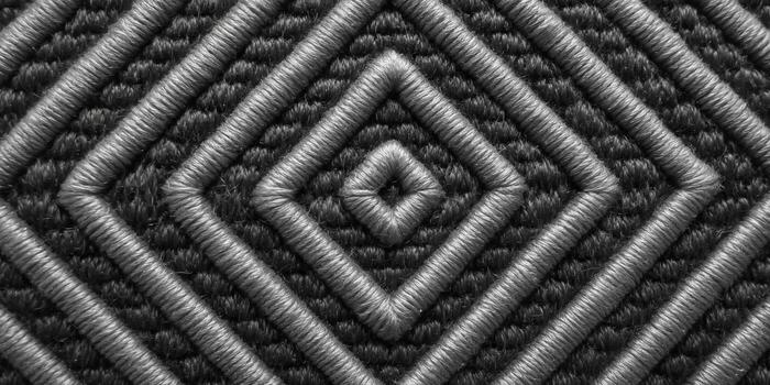 An artistic display of diamond pattern embroidery in shades of gray and black, creating an appealing texture. photo