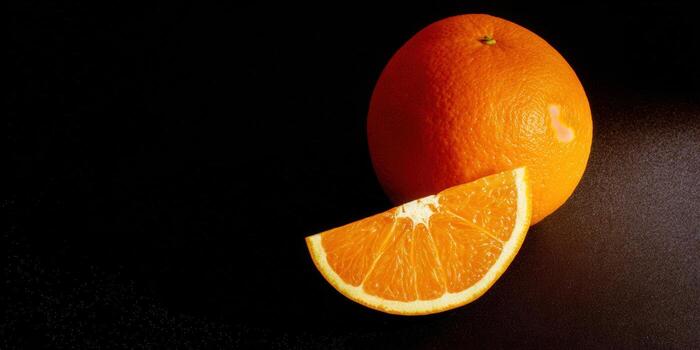 A whole orange and a slice of citrus on a dark, textured background. photo