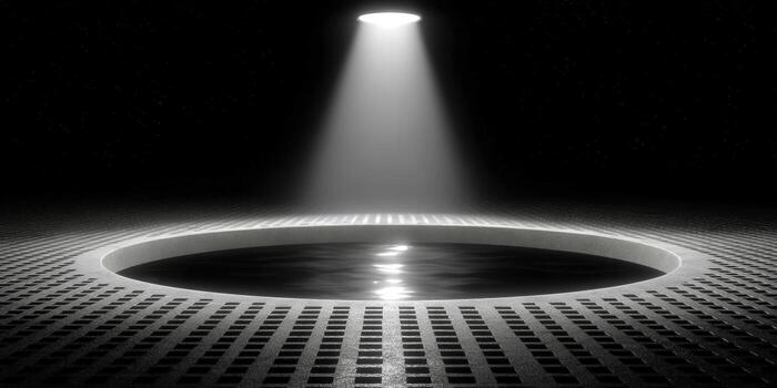 Dramatic spotlight shines on a circular platform in a minimalist black and white scene. photo