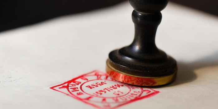 Close-up of a vintage stamp pressing on paper, creating a red seal photo