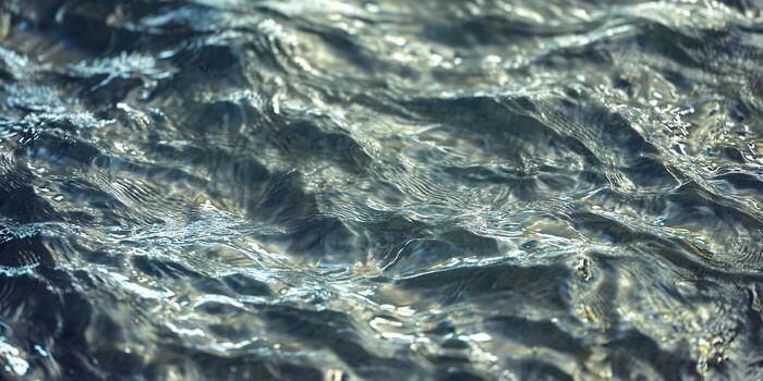 Captivating close-up of rippling water, revealing intricate wave patterns and reflections. photo