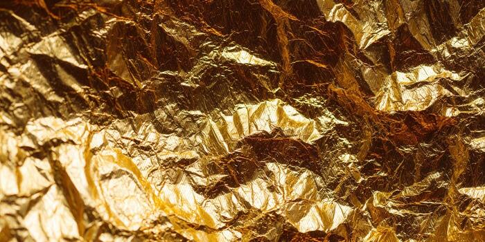 Crumpled gold foil background with textured, metallic surface and highlights photo