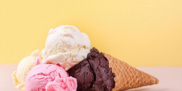 Close-up of a colorful ice cream cone with different scoops of flavors on a light background. photo