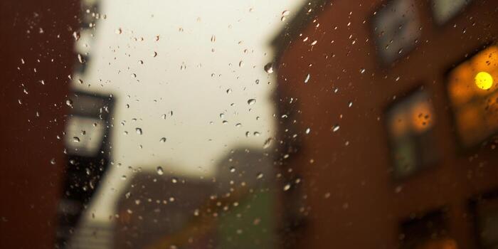 Rain-covered window with blurred city lights creates a warm and inviting atmosphere. photo