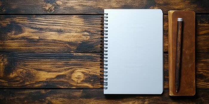 Blank notebook with a pen, ready for writing, resting on a wooden desk. photo