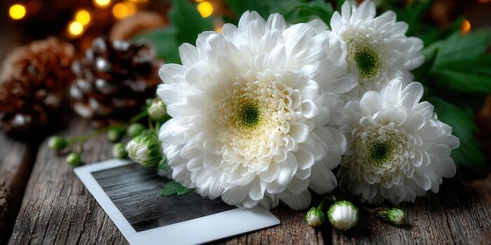 A beautiful arrangement of white chrysanthemums rests on a wooden surface with a polaroid. photo