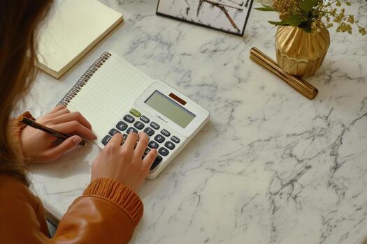 A woman is using a calculator on a desk photo