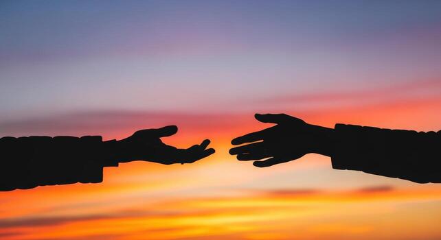 Silhouette of Two Hands Reaching Out Against a Colorful Sunset Sky, Expressing Connection and Support photo