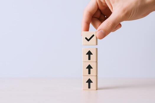 Hand placing checkmark block atop upward arrow blocks symbolizing success and growth achievement photo