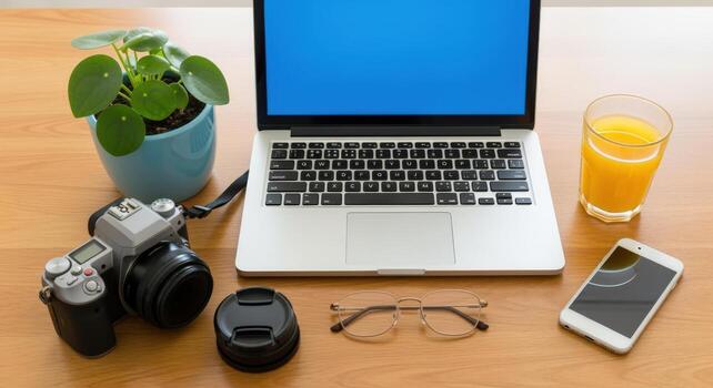 Workstation composition with laptop, camera, smartphone, drink and plant, demonstrating a creative workflow and modern office setup photo