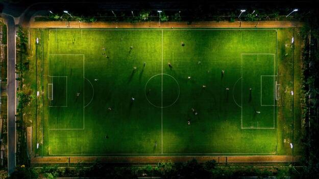 Aerial View of a Soccer Field at Night with Players Under Stadium Lights Playing Match photo