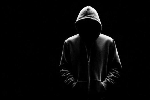 misterioso figura en capucha con cara oscurecido por oscuridad en un negro fondo foto