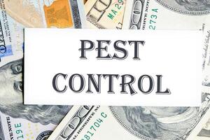 Pest control phrase written on a white card against the background of banknotes photo