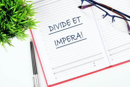 Latin quote Divide et impera meaning Divide and conquer. the best method of governing such a state is to incite and use hostility between its parts. Text written in a notebook on the table photo