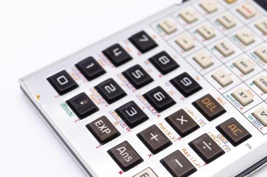 Close-up of a Silver Calculator with Black Buttons on a White Background Showing Numbers and Functions. photo