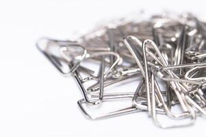 pila de plata papel clips en blanco antecedentes oficina suministros todavía vida. foto