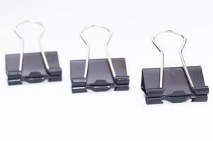 Tres negro aglutinante clips en un blanco antecedentes oficina suministros papel organización de cerca vista. foto