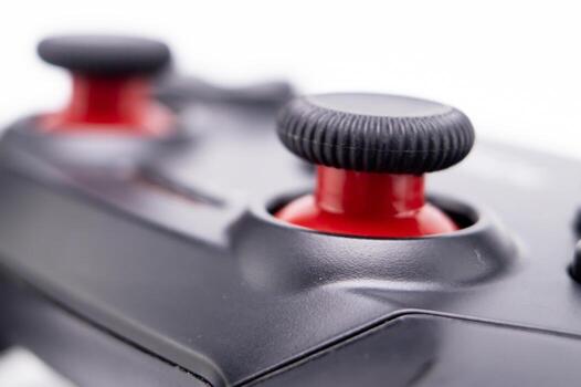 Close-up of a Black and Red Game Controller with Textured Joysticks on White Background. photo