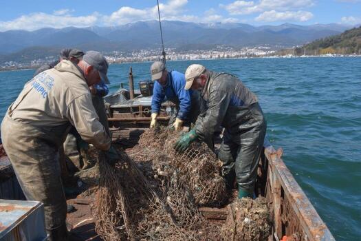 Three men are loading nets onto a boat photo