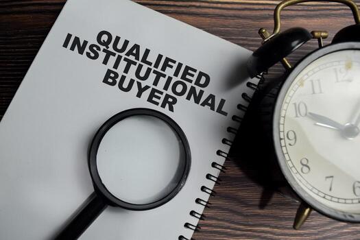 Concept of qualified institutional buyer write on book isolated on Wooden Table. photo