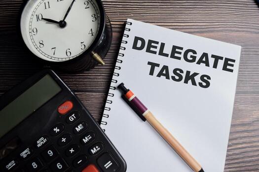 Concept of Delegate tasks write on book isolated on Wooden Table. photo