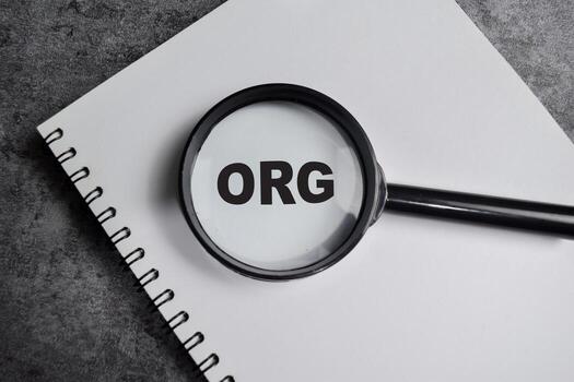 Concept of ORG with magnifier write on clipboard isolated on Wooden Table. photo
