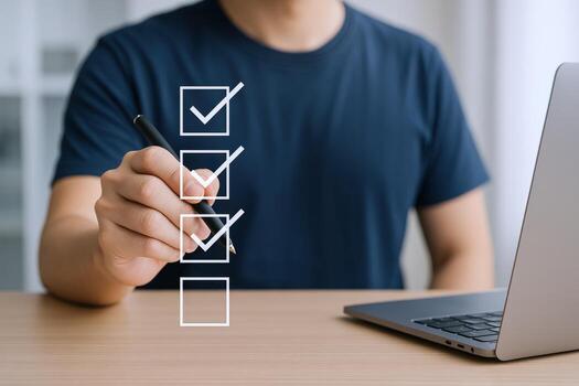 Man Completing Digital Checklist with Pen Near Laptop Demonstrating Task Management and Productivity photo
