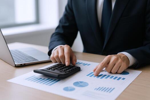 Financial Analyst Reviewing Business Performance Charts and Data with Calculator and Laptop on Desk photo