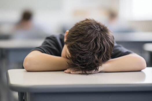 Tired Student Resting Head on Desk in Classroom, Demonstrating Exhaustion, Burnout, and Academic Struggles photo