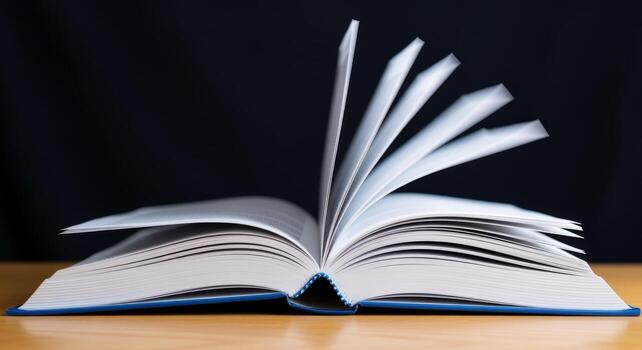 Open Book with Turning Pages on Wooden Table Against Dark Background, Representing Learning and Education photo