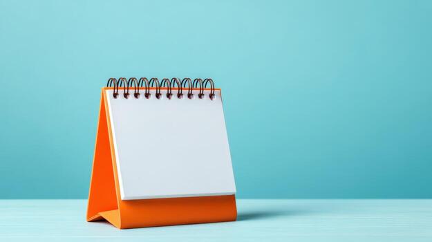 Blank Orange Desktop Calendar Mockup Against Blue Background for Planning and Scheduling Concepts photo
